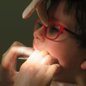 Dentista mexendo no aparelho dental na boca de uma criança