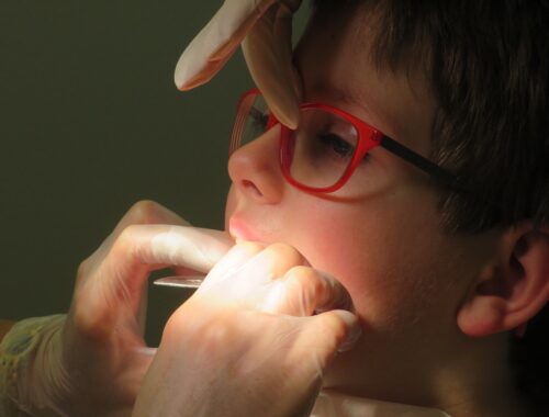 Dentista mexendo no aparelho dental na boca de uma criança